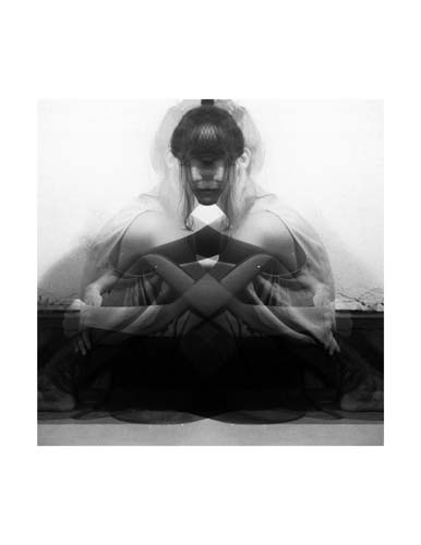 A picture of a girl is doubled and reflected, her face and arms intersecting in a black and white portrait.