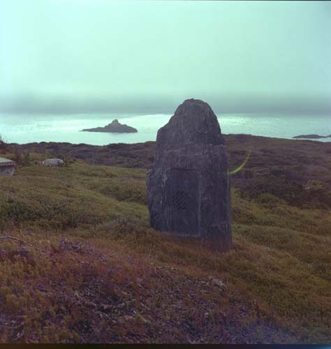 A tombstone sits in front of a view of the ocean